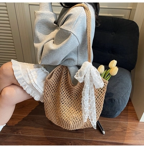Gros plan d'un sac cabas en paille tissé à la main avec un nœud en dentelle blanche
