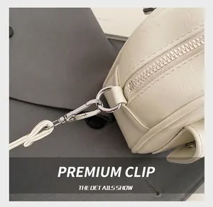 Detail view of silver metal hooks and high-quality zipper on cream-colored PU leather bag