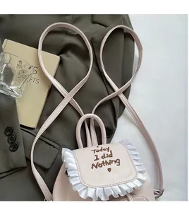Dettaglio mini zaino rosa con scritte ricamate e bordi decorativi con volant bianchi