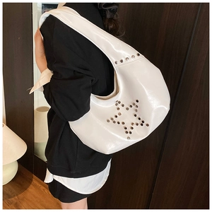 Close-up of a white star rivet shoulder bag styled on a model in a cozy interior