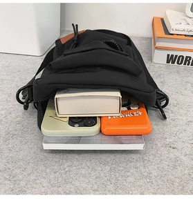 Detail showing high-capacity interior of the black nylon shoulder bag with a phone and book