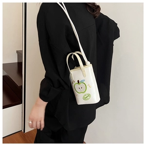 Detail of white mini bucket bag with green apple embroidery and thin shoulder strap