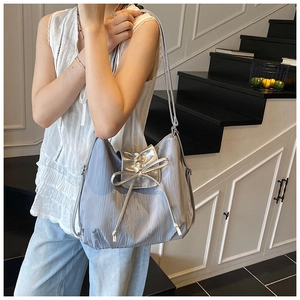 Detail of silver-blue metallic tote bag with leather bow decoration on shoulder strap