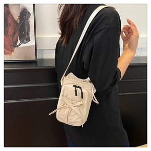 Detail view of beige nylon crossbody bag featuring drawstring closure and bow pocket detail