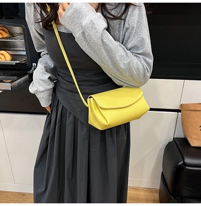 Détail du sac bandoulière en cuir grainé jaune avec rabat minimaliste sur le modèle