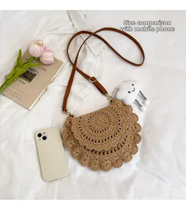 Detail of a half-moon straw woven crossbody bag with cute cloud charm and leather strap