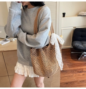 Détail d'un sac cabas tissé avec un nœud en dentelle blanche sur la poignée marron