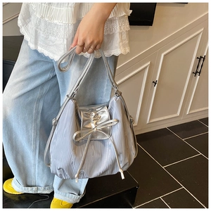 Detail of silver metallic tote bag with liquid ripples, bow decoration, and drawstring