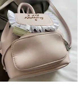 Dettaglio ravvicinato dello zaino in pelle PU rosa con ricamo I Did Nothing e fronzoli