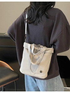 Minimalist beige drawstring bucket tote bag with detachable shoulder strap shown on model