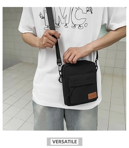 Detail of black crossbody bag with adjustable strap and front pocket close-up