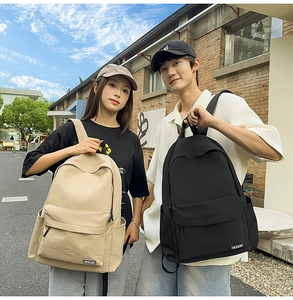 Outdoor shot of models wearing black and beige minimalist school backpacks with side pockets