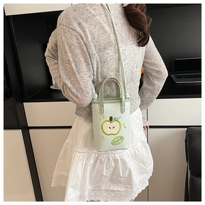 Close-up of mint green apple-shaped bucket bag with embroidery and thin strap
