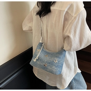 Detail of light blue denim hobo bag featuring silver metallic butterfly accents and glittery finish