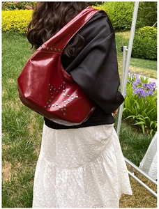 Detail view of red patent leather shoulder bag with star-shaped metal rivets