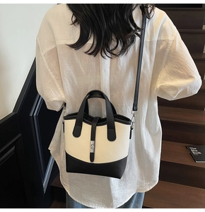 Close-up of a two-tone bucket bag in pebbled leather with silver twist lock and straps