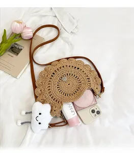 Detailed top view of a round straw woven bag with leather strap and cloud charm detail