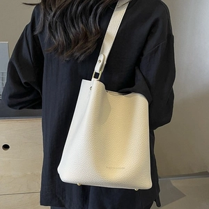White lychee pattern bucket bag with wide strap and fashion lettering on back of model