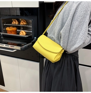 Détail d'un sac bandoulière jaune en cuir grainé présenté dans un cadre de vie moderne