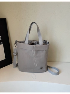 Versatile grey nylon bucket tote bag with drawstring closure and adjustable crossbody strap