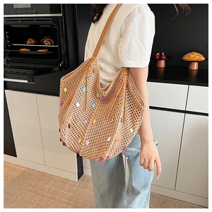 Close-up of knit tote bag with colorful sequins and brown leather shoulder straps