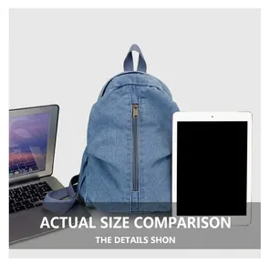 Détail du sac à dos en jean bleu avec poche zippée verticale à côté d'un ordinateur