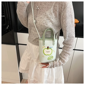 Detail of light green apple-shaped embroidered bucket bag with crossbody strap and top handle