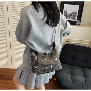 Détail d'un sac hobo gris scintillant orné de papillons en métal argenté 3D