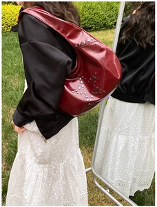 Macro detail of red glossy leather shoulder bag with silver star rivet studs