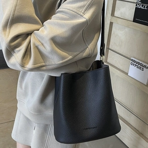 Black pebbled leather bucket bag with gold hardware worn by model in casual style