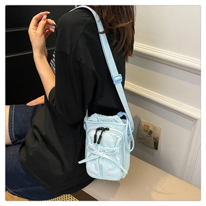 Detail of light blue nylon crossbody bag with drawstring closure and bow decoration