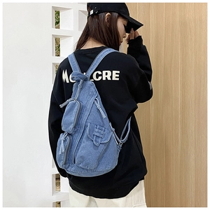 Detail eines hellblauen Denim-Rucksacks mit funktionellen Taschen und verstellbaren Trägern