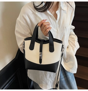 Detailed close-up of a two-tone bucket bag featuring cream leather and black accents
