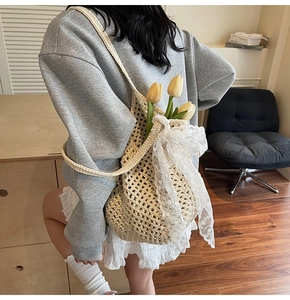 Détail du sac cabas en maille beige avec un grand nœud en dentelle blanche et des tulipes