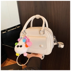 Detail of creamy white PU leather mini bag with plush heart charm and front pocket