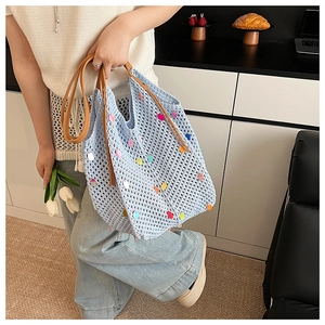 Détail du sac cabas en crochet bleu clair avec pois colorés et anses en cuir brun