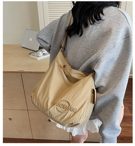 Dettaglio della borsa tote in tela kaki con logo in metallo indossata da una modella