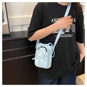 Detail of light blue drawstring crossbody bag with decorative bow and waterproof fabric