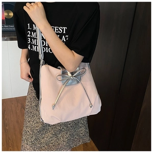 Model view of pink pleated tote bag with silver metallic bow and adjustable strap