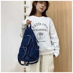 Detailansicht der dunkelblauen Denim-Brusttasche mit vielen Taschen am Model