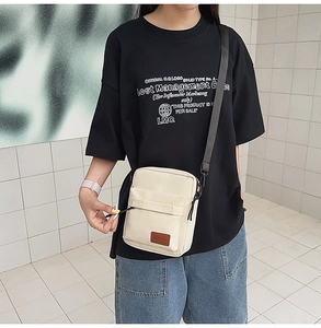 Minimalist beige canvas crossbody phone bag shown on a model with adjustable black strap