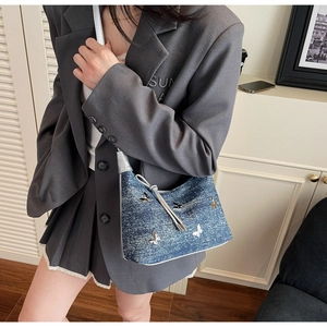 Détail du sac à bandoulière en jean avec papillons argentés et franges au style Y2K