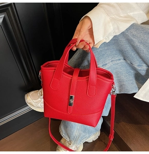 Detail view of red lychee grain bucket bag with silver metal lock and long strap