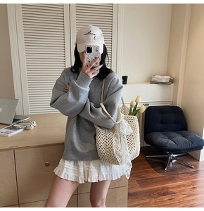 Gros plan d'un sac cabas en crochet beige avec des nœuds en dentelle et détails floraux