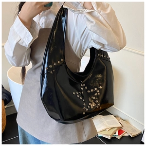 Close-up of silver star rivets and polished black leather texture on the shoulder bag