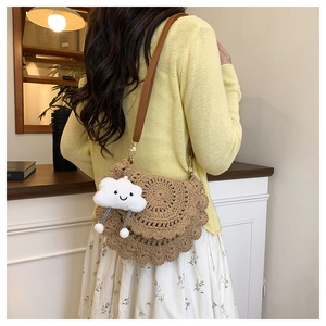 Detail of hand-woven crochet crossbody bag in earthy brown with a plush cloud charm