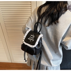 Close-up of black mini backpack featuring white ruffled edges and creative lettering detail