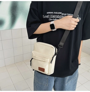 Detail of minimalist beige canvas crossbody bag showing texture and adjustable strap