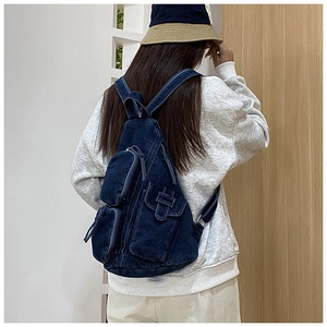 Detail eines dunkelblauen Denim-Rucksacks mit Multi-Taschen-Design auf dem Rücken