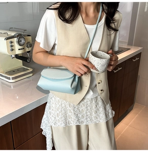 Détail du sac bandoulière en cuir bleu clair à motif litchi dans une scène de vie